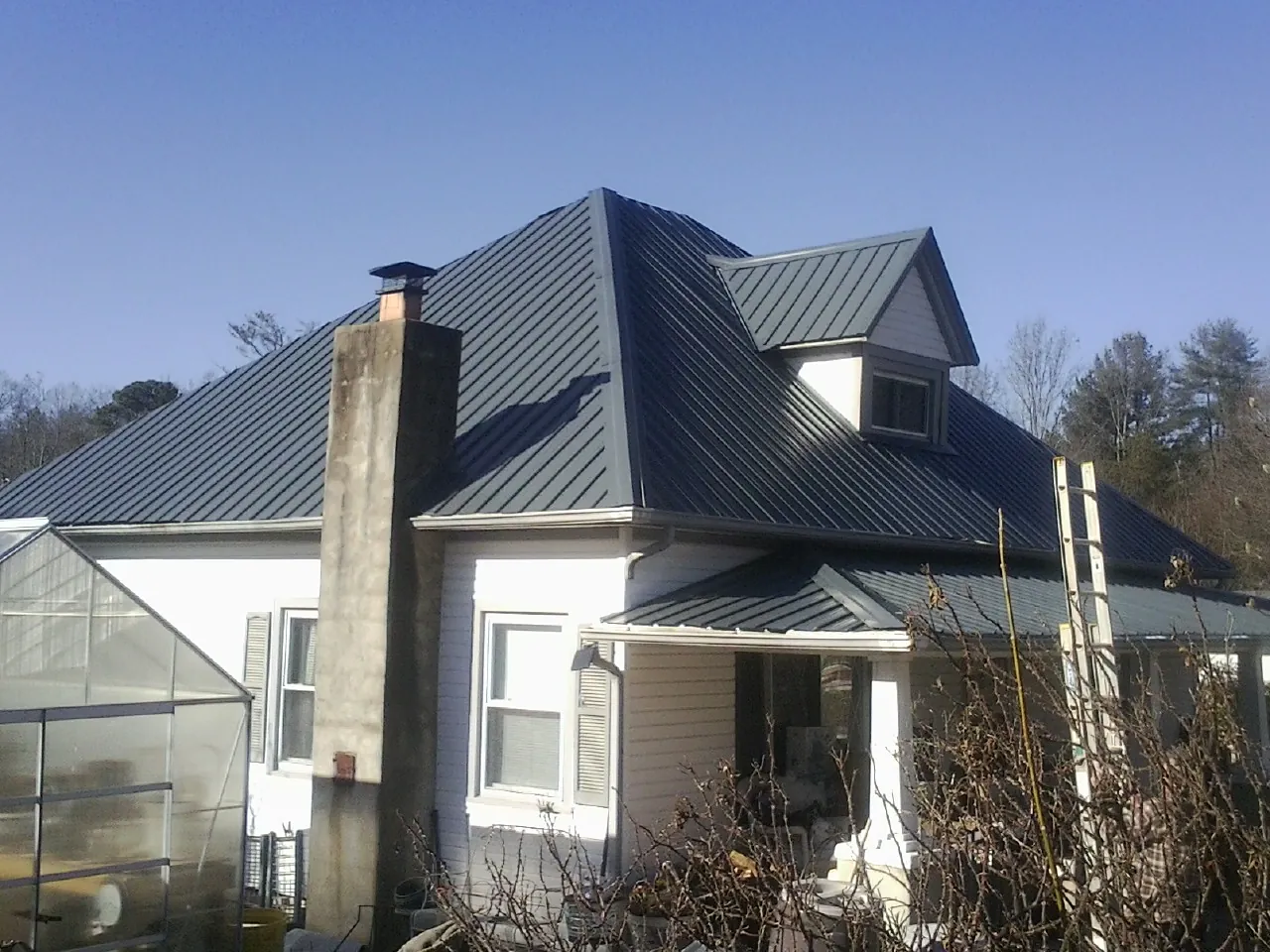 Dark blue standing seam metal roof on a white farmhouse with dormer — Slate & Tile Roof Repair by Roofing Brothers in Rothsay