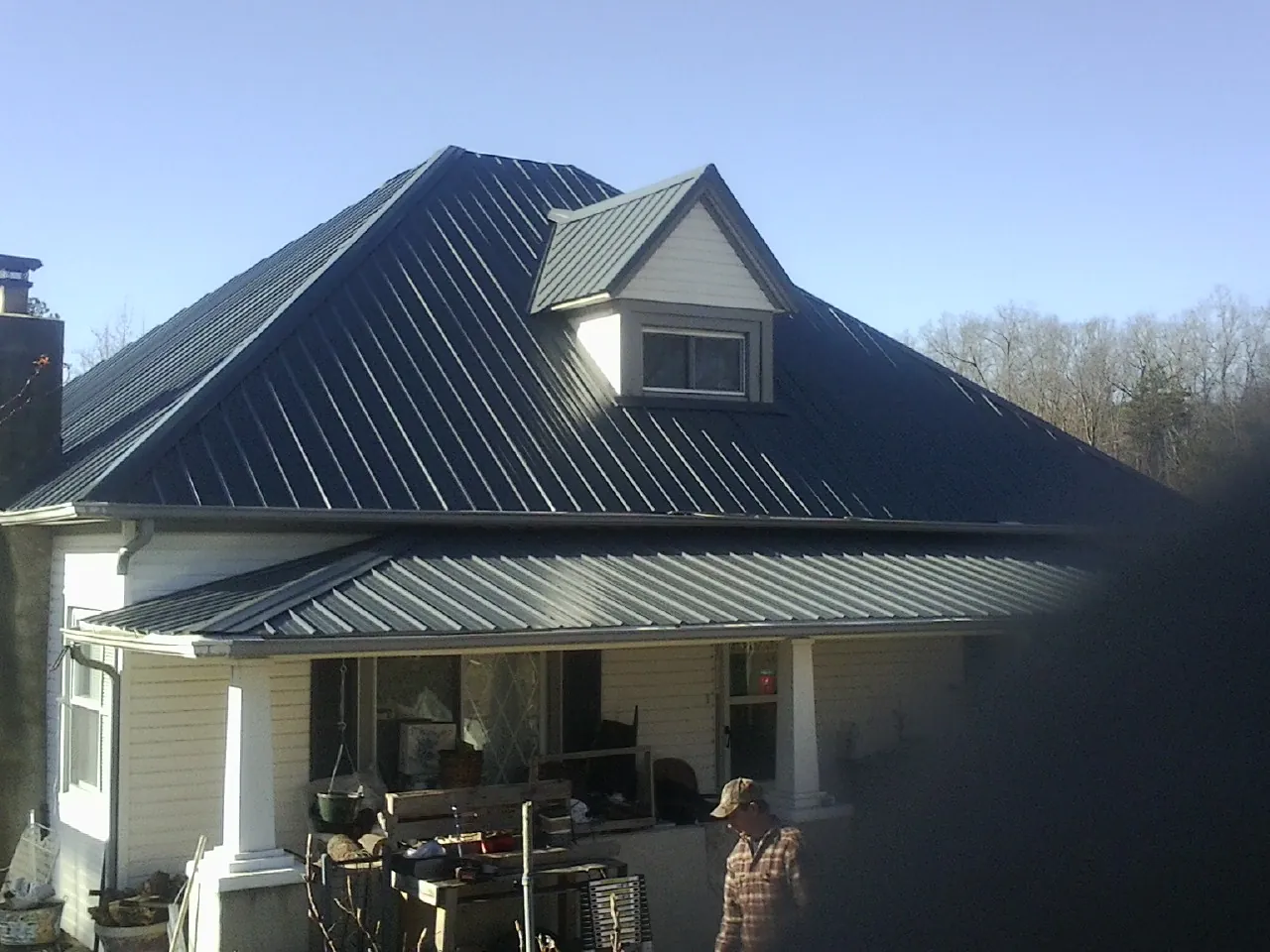 Dark blue standing seam metal roof with a dormer above a front porch in Rothsay