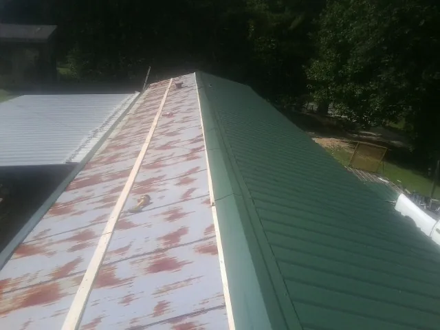 Old rusted panels beside newly installed green metal roofing — Wind Damage Roof Repair by Roofing Brothers in Rothsay