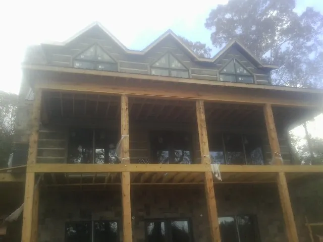 Dormers and porch framing on a large log home under construction — Roof Coating work by our crew in Rothsay