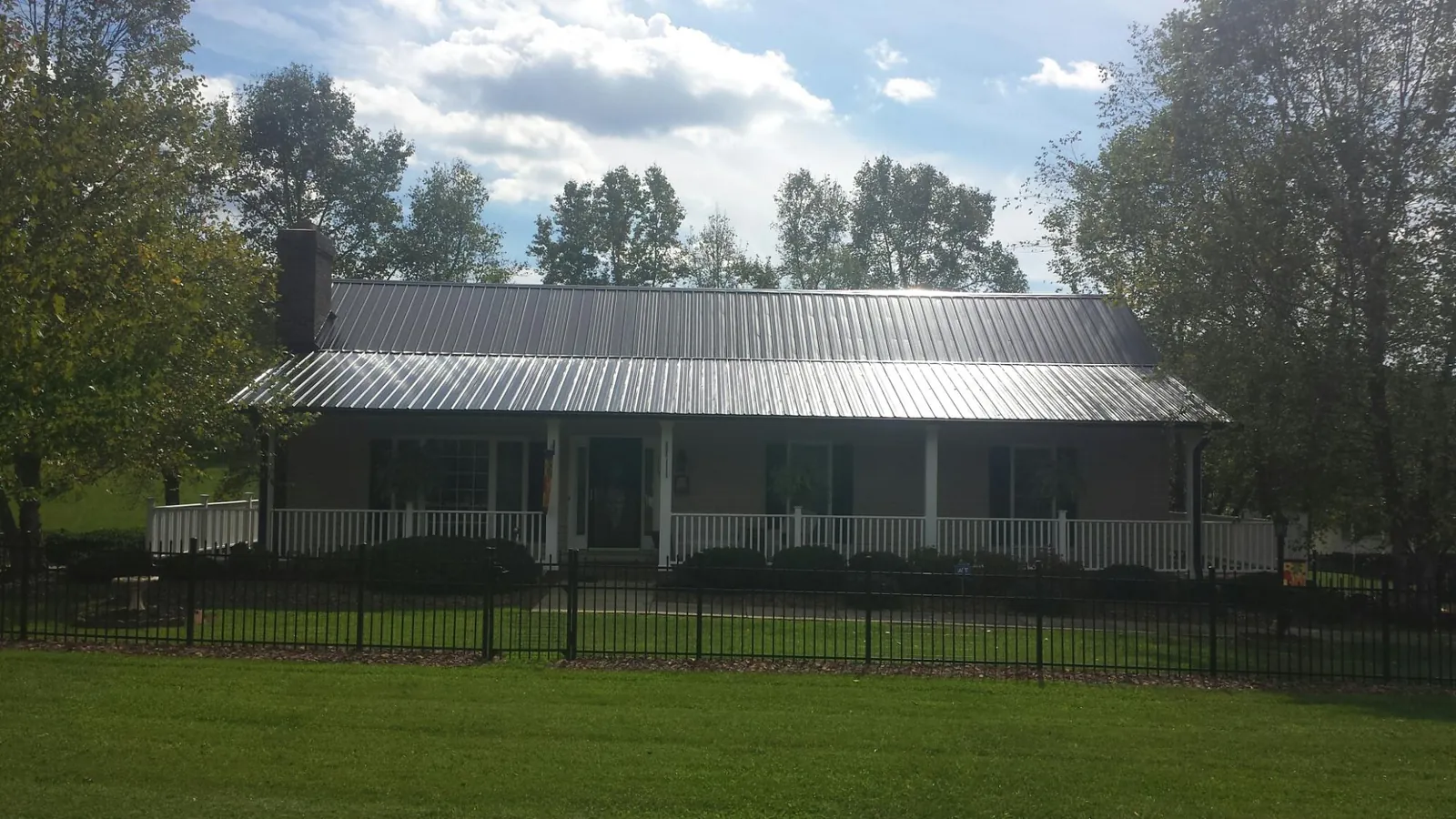 Gray metal roof on a brick ranch with a full width front porch — Gutter Guard Installation work by our crew in Rothsay