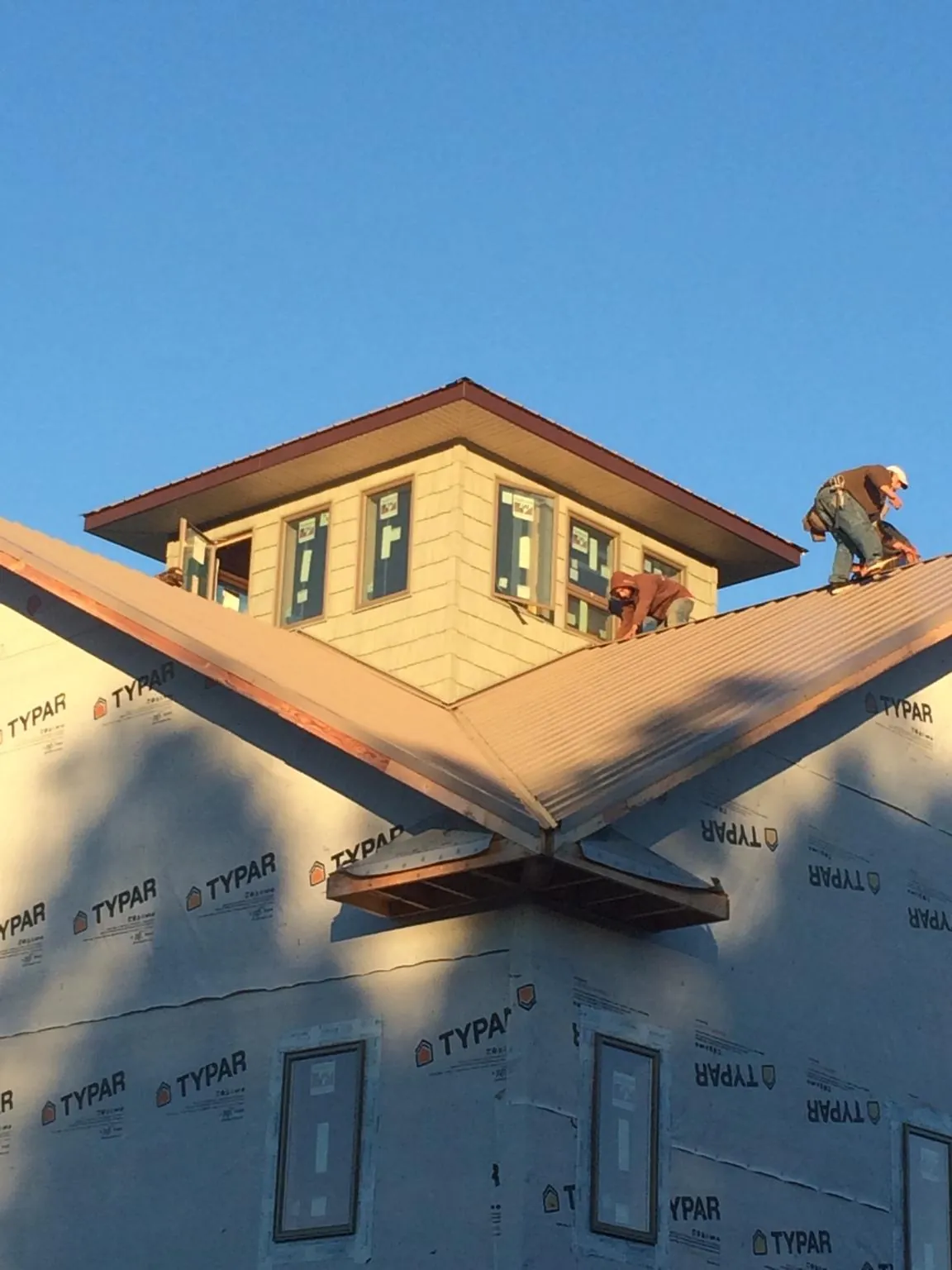 Roofers working around a rooftop cupola on a new metal roof at sunset — Roof Waterproofing in Rothsay by Roofing Brothers